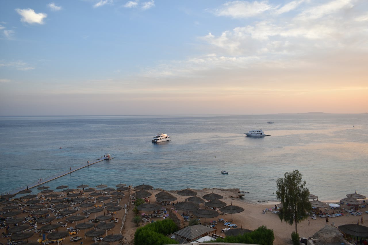 Stunning aerial view of Sharm El Sheikhs beach and sea during sunset with boats and parasols.