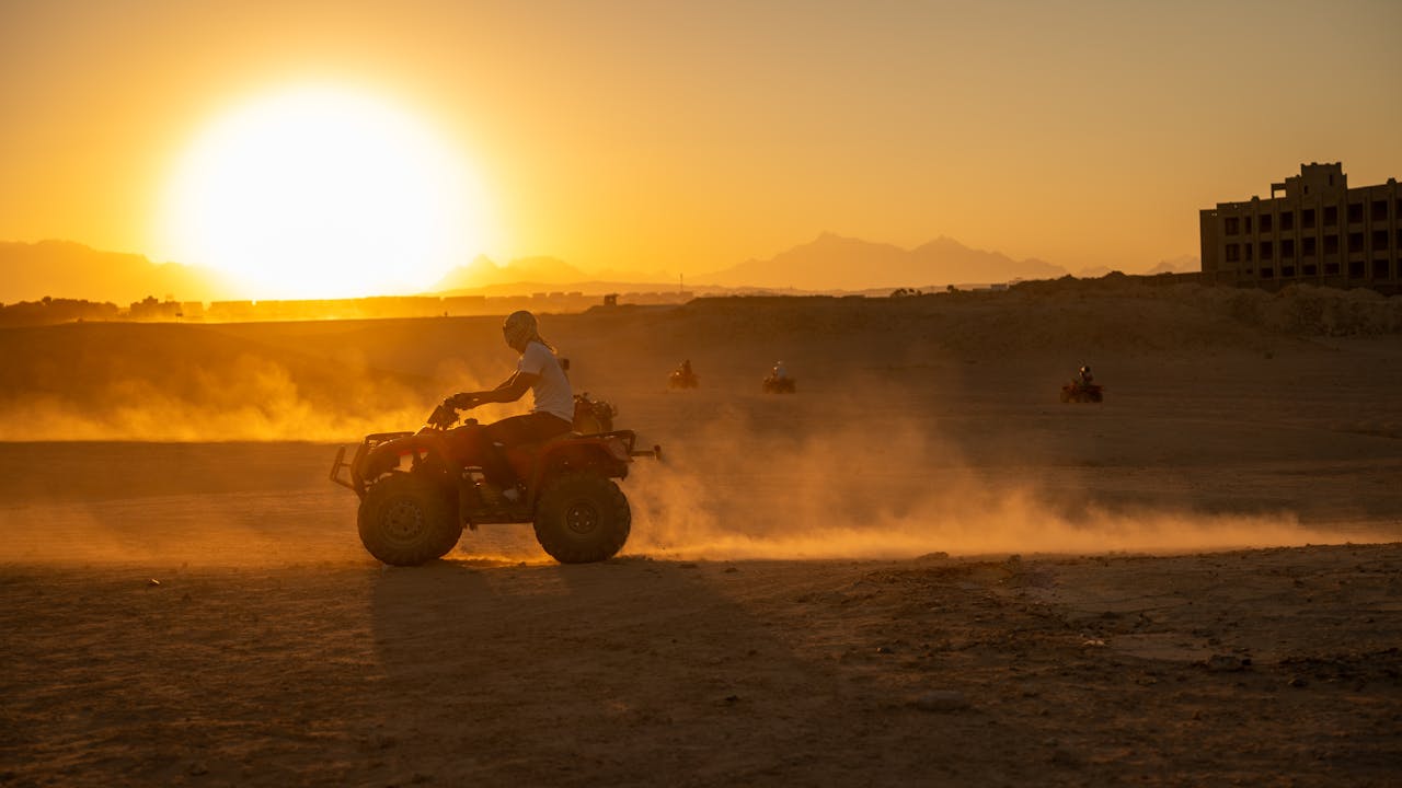our-mission-01 ATV riders explore the desert landscape at sunset, creating a scene filled with dust and motion.