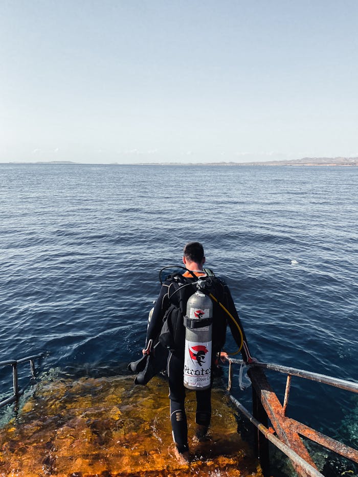 our-story-02 A scuba diver in a drysuit embarking on a diving adventure from a step in Sharm El-Sheikh, Egypt.